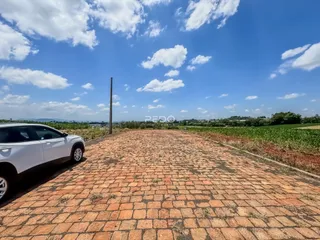 Vista aérea da propriedade com um pátio de tijolos e campos ao fundo.