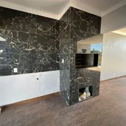 Parede de mármore escuro com piso de madeira em um ambiente interno.