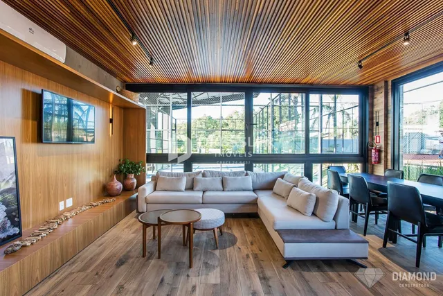 Sala de estar com piso de madeira e grandes janelas que dão vista para o exterior.