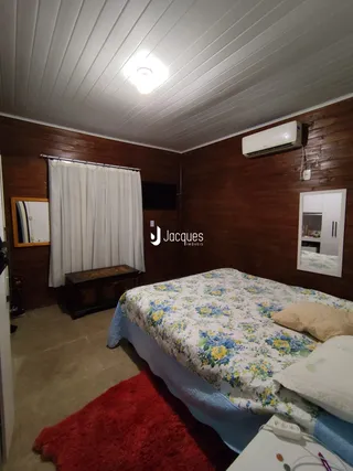 Quarto com cama e cortinas em ambiente de madeira.