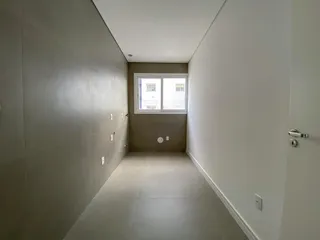 Foto de um corredor interno com paredes claras e piso liso.