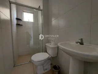 Banheiro com revestimento branco e box de vidro transparente.