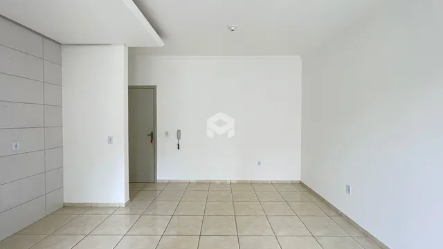 Interior de uma sala com piso de cerâmica e parede branca.