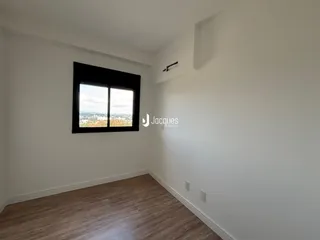 Sala de estar com piso de madeira e janela com vista para a cidade.