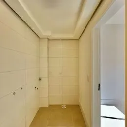 Foto de um corredor interno com paredes brancas e piso claro.