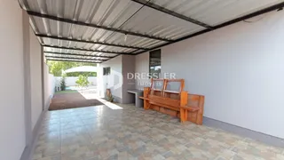 Área coberta com piso de cerâmica e banco de madeira.