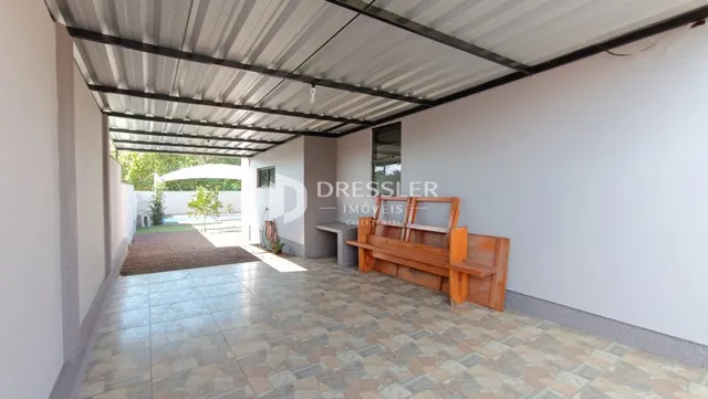Área coberta com piso de cerâmica e banco de madeira.