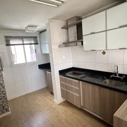Uma cozinha com armários e bancadas em madeira clara e piso de madeira clara.