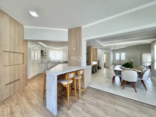 Ambiente moderno de sala de jantar e cozinha com piso de madeira clara.