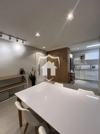 Uma sala de jantar com mesa branca e cadeiras brancas.