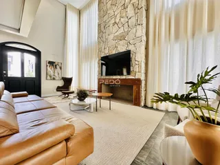 Sala de estar com grandes janelas e parede de pedra em um imóvel em Lajeado.
