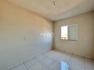 Interior de uma sala com piso de cerâmica clara e paredes brancas.