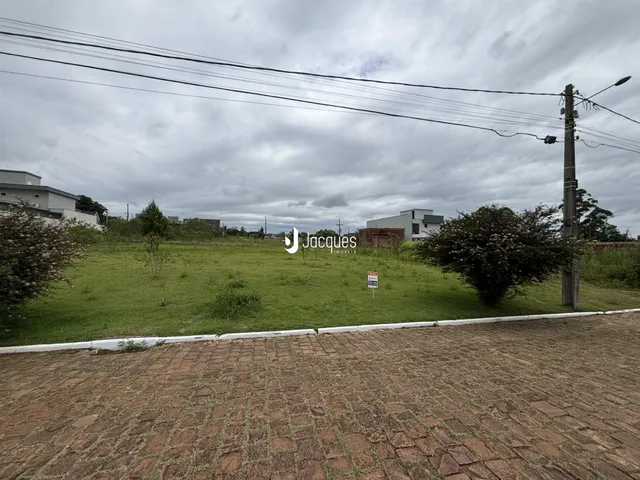 Área externa de um terreno gramado com cerca e postes de luz.