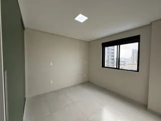 Sala ampla com piso de cerâmica e janela com vista para a paisagem urbana.