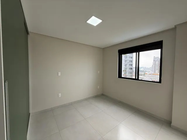 Sala ampla com piso de cerâmica e janela com vista para a paisagem urbana.