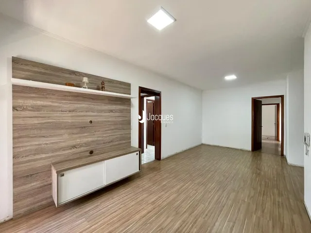 Ambiente interno de uma sala com piso de madeira clara e paredes brancas.
