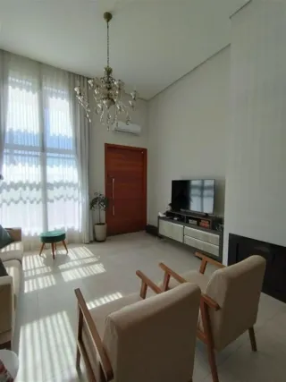 Sala de estar iluminada com cortinas claras e um lustre no teto.