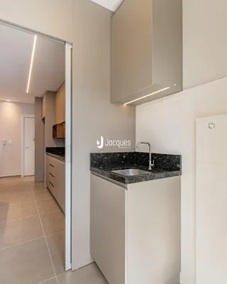 Cozinha moderna com armários brancos e bancada escura.
