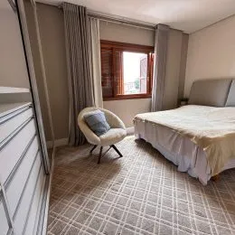 Quarto interno com piso de carpete e cortinas claras.