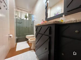 Foto de um banheiro com revestimento cerâmico e box de vidro.