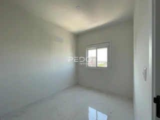 Sala de estar com paredes brancas e piso claro.