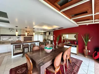 Uma sala de jantar com mesa de madeira e cozinha moderna.