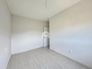 Ambiente interno com paredes brancas e piso de madeira clara.