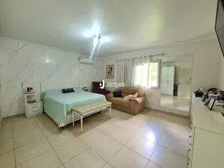 Quarto com cama e sofá em ambiente claro com paredes de mármore branco