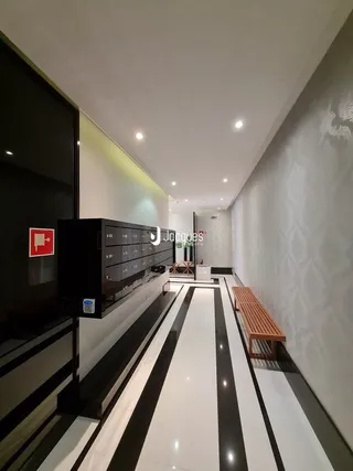 Corredor interno com piso em listras pretas e brancas.