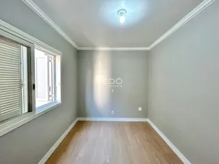 Ambiente interno de uma sala com piso de madeira clara e janela.