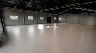 Foto de um espaço amplo e industrial com piso claro e paredes cinzas.