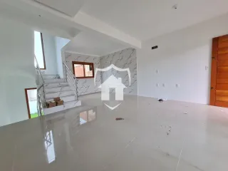 Ambiente interno de uma sala ampla com piso de porcelanato e escadaria.