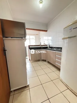Foto interna de uma cozinha com armários e piso de cerâmica clara.