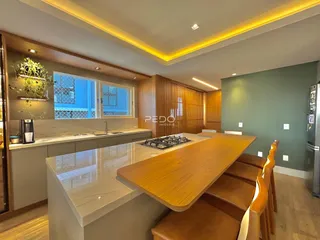 Vista de uma cozinha moderna com bancada de madeira e iluminação em LED.