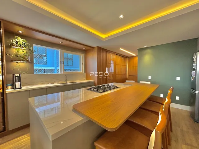 Vista de uma cozinha moderna com bancada de madeira e iluminação em LED.