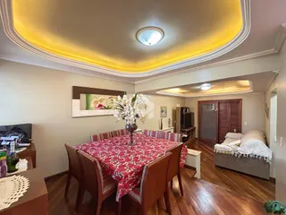 Sala de jantar com piso de madeira e decoração de teto.