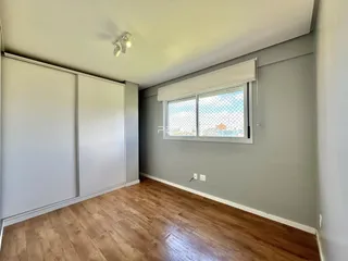 A sala apresenta paredes cinzas e piso de madeira clara.