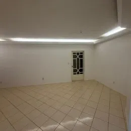 Foto de um ambiente interno vazio com piso de cerâmica claro e iluminação embutida.