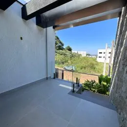 Varanda externa com piso claro e estrutura de teto branca.