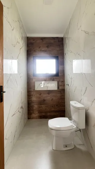 Hall de banheiro com paredes brancas e detalhes em madeira.