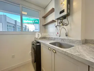 A cozinha apresenta armários brancos e bancadas claras.