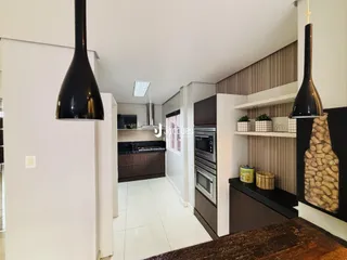 Vista de uma cozinha moderna com armários escuros e piso branco.