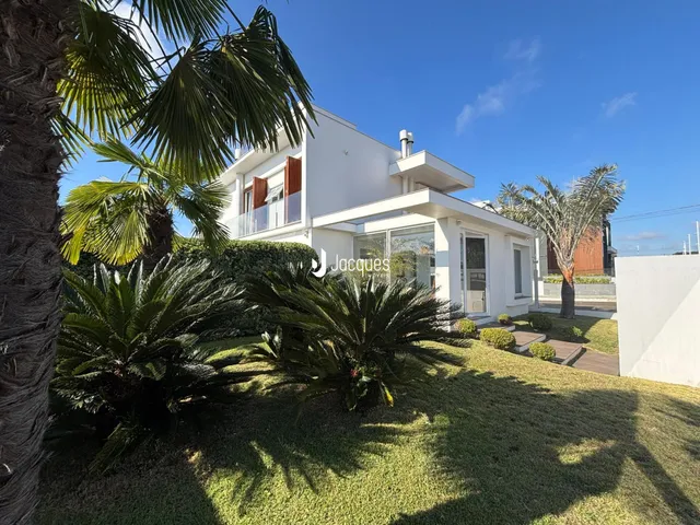 Fachada de uma casa moderna branca em Lajeado, Brasil, com jardim exuberante.