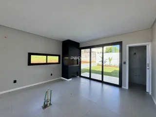 Sala de estar ampla com piso claro e portas de vidro que dão para o jardim.