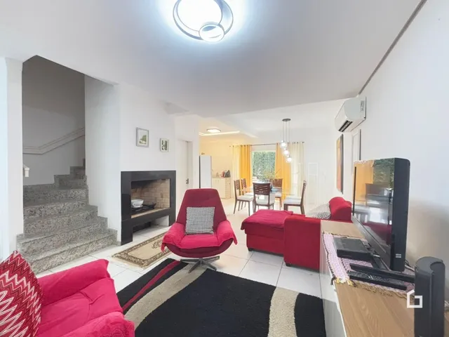 Sala de estar com lareira e escadaria em um imóvel no Brasil.