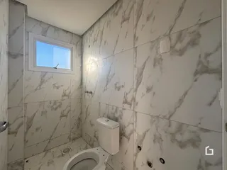 Foto de um banheiro com revestimento de mármore claro.