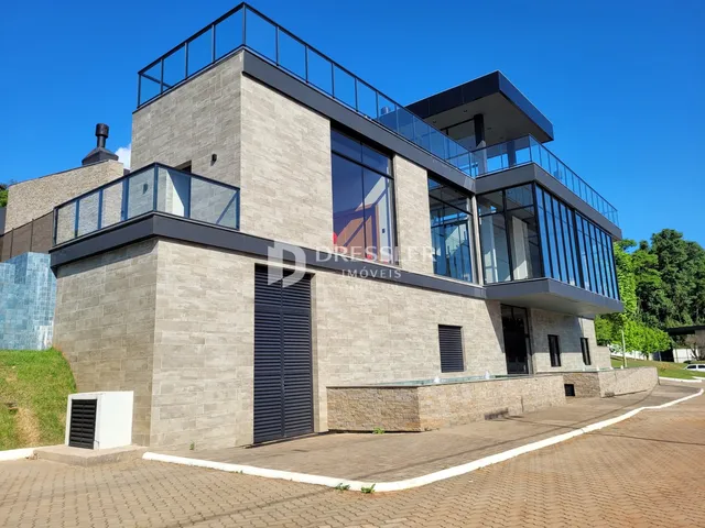 Fachada moderna de um imóvel em Lajeado, Brasil, com revestimento de pedra e grandes janelas de vidro.