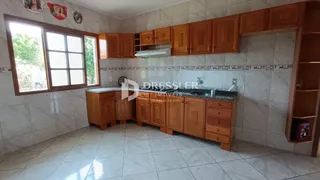 Vista da cozinha e sala de jantar com armários de madeira e piso de cerâmica.