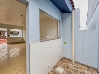 Vista de um corredor interno com parede azul e piso de pedra em uma propriedade no Brasil.