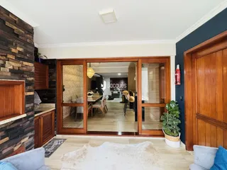 Interior de uma sala com parede de pedra e piso de madeira clara.